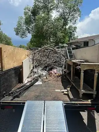 Trailer bed loaded with branches, board and furniture ready to leave site