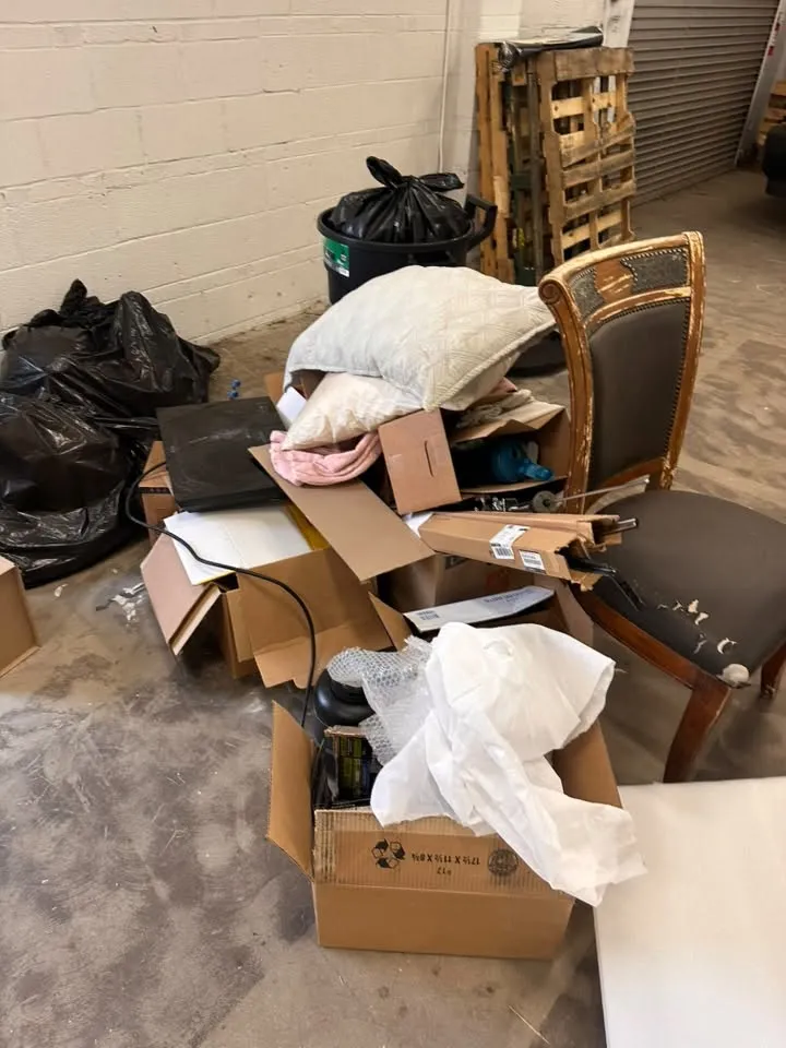 Bin bags, open boxes, pillows and an old wooden chair on a warehouse floor in Denver