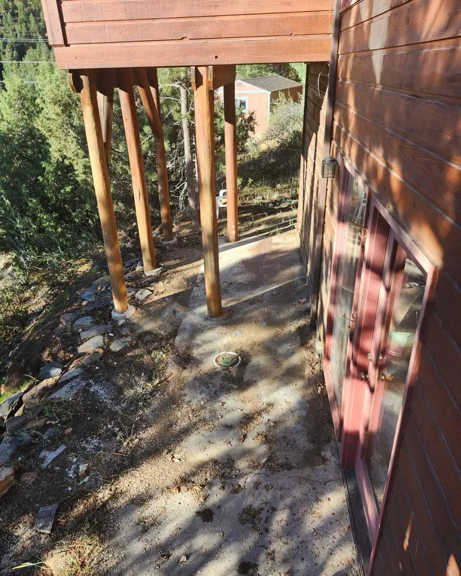 The bare concrete pad under a raised deck in Evergreen after the hot tub was removed, swept clean